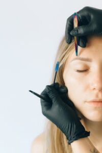 Close-up of a woman receiving professional eyebrow and lash treatment in a beauty salon.